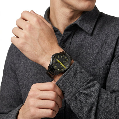 A close-up of a man wearing a dark gray heathered long-sleeve shirt and adjusting his cuff while wearing a black watch with a black strap and a bright yellow dial.