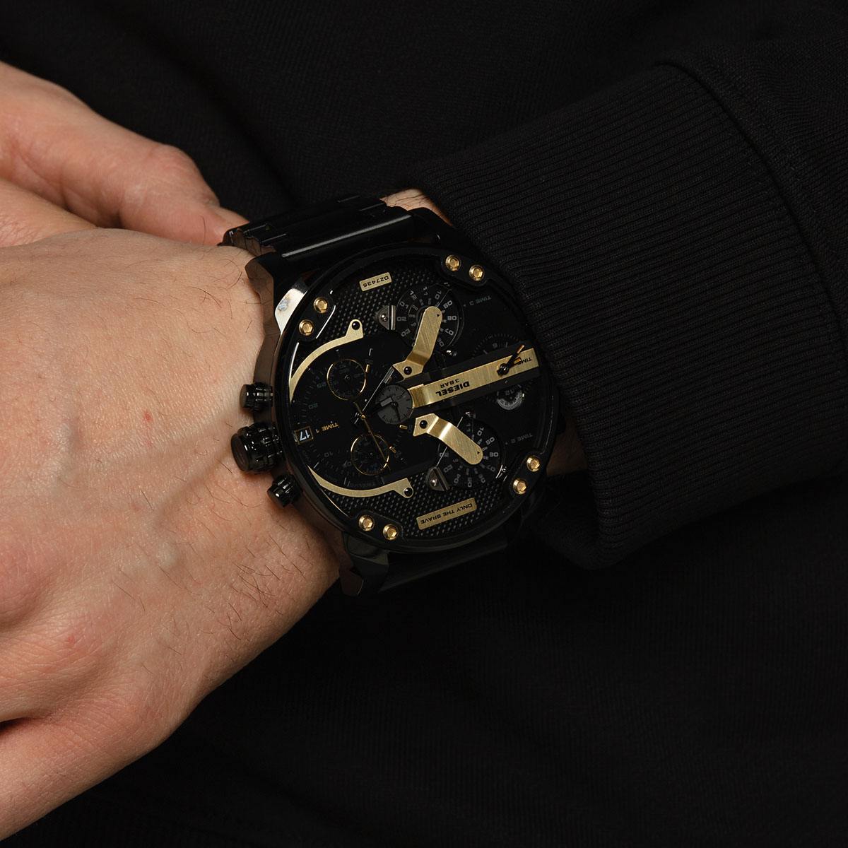 Close-up of black chronograph watch with multiple dials and gold-tone hands worn on wrist