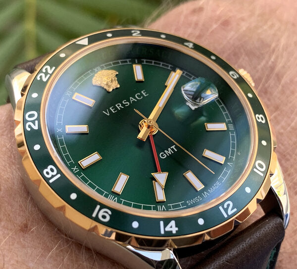 Versace Hellenyium watch on wrist showing green dial, gold and silver case, and GMT hand